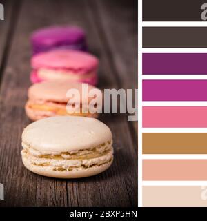 Macaroni francesi su un vecchio sfondo di legno. In una tavolozza di colori con campioni di colore omaggio. Foto Stock