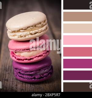 Macaroni francesi su un vecchio sfondo di legno. In una tavolozza di colori con campioni di colore omaggio. Foto Stock