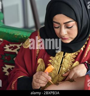 Mosca, Russia - 14 luglio 2018: Una donna henné o un'applier mehndi del Qatar al lavoro. Processo di applicazione dell'hennè tradizionale Mehndi sulla mano femminile Foto Stock