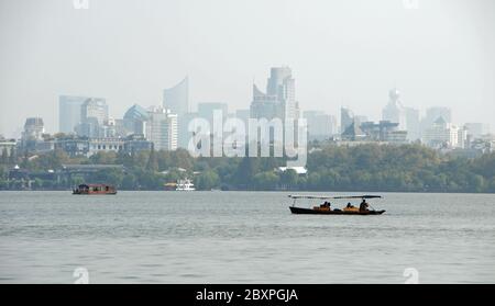 Lago occidentale (Xi Hu) a Hangzhou, provincia di Zhejiang, Cina. Barche sul Lago Ovest con la città di Hangzhou alle spalle. Foto Stock