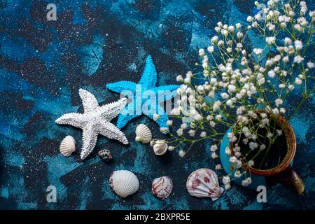 Bella composizione marina. Conchiglie, stelle marine, spazio copia su sfondo blu scuro. Concetto di viaggio e avventura Foto Stock