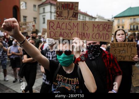 I manifestanti in maschere mediche tengono i cartelli con slogan che condannano il razzismo. Centinaia di giovani hanno partecipato alla protesta 'Black Lives Matter' a Crac Foto Stock
