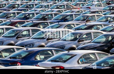 File di nuove auto parcheggiate in un centro di distribuzione in una fabbrica di automobili in una giornata di sole. Parcheggio all'aperto. Foto Stock