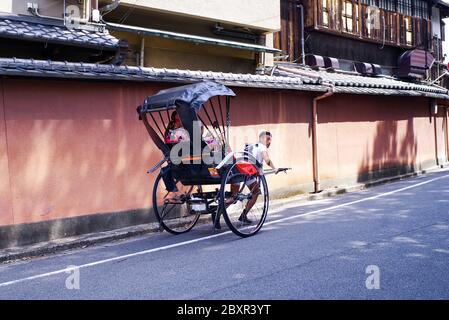 Giappone, Kyoto. 2018. I risciò sono popolari in Kyoto.Japan, Kyoto. 2018. Il risciò giapponese corre una ragazza in giù per la strada in una carrozza. Foto Stock