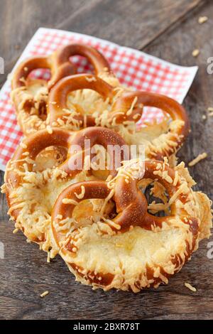 Deliziosi pretzel morbidi con formaggio su sfondo di legno Foto Stock