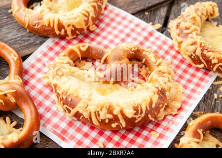 Deliziosi pretzel morbidi con formaggio su sfondo di legno Foto Stock