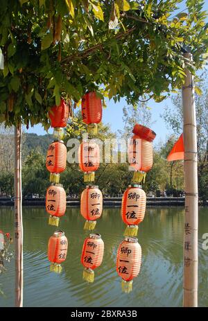 Hongcun Antica Città nella Provincia di Anhui, Cina. Lanterne rosse appese fuori da una vecchia casa di Hongcun con il lago Nanhu alle spalle Foto Stock