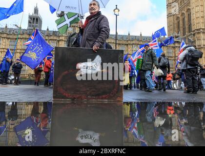 Artista e pittore Kaya Mar con uno dei suoi dipinti satirici che commentano la Brexit, fuori dal Parlamento, Westminster Foto Stock