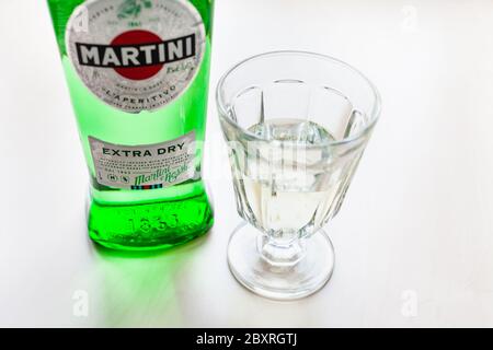 MOSCA, RUSSIA - 23 MAGGIO 2020: wineglass con bevanda e bottiglia di Martini Extra Dry su tavolo marrone chiaro. Martini è il classico vermouth italiano di Turin Foto Stock