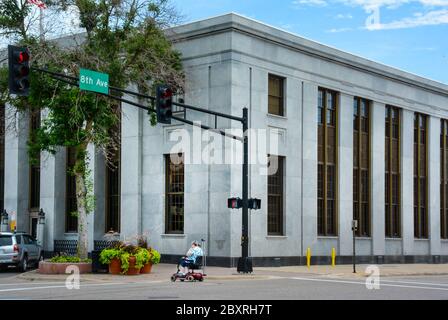 Un anziano in uno scooter per la mobilità attraversa la 8th Avenue di fronte allo storico edificio USPO nel centro di St. Cloud, Minnesota, USA Foto Stock