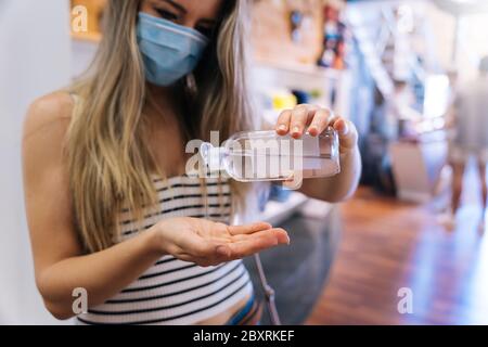 Donna disinfettando le mani con gel idroalcolico nella pandemia del coronavirus Foto Stock