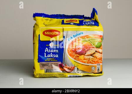 Kuching, Sarawak / Malesia - 26 aprile 2020: halal istante noodle sour speziato laksa sapore del marchio maggi in un pacchetto giallo e blu su grigio backgro Foto Stock