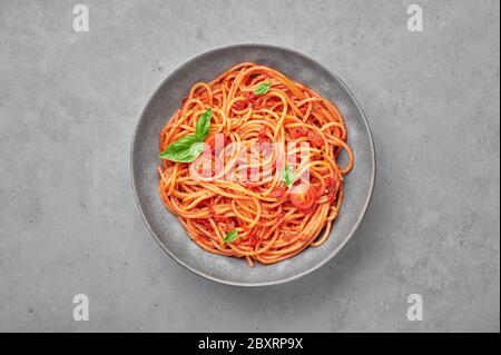 Spaghetti di pomodoro in ciotola grigia su fondo di cemento. La pasta con salsa di pomodoro è un piatto classico della cucina italiana. Popolare cucina italiana Foto Stock