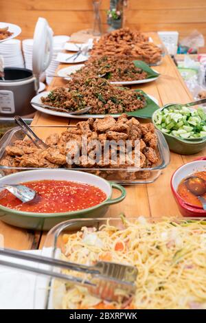 Scopando sul mucchio di pasta di pesce tailandese fritto polpette di carne in vetro piatto triangolo e gli altri cibo tailandese accanto e intorno ad esso. Tutti sono in attesa per lu Foto Stock