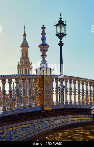 Frammento di ponte decorato con piastrelle di ceramica blu bianco attraverso il fiume Guadalquivir e vista della torre, dettagli architettonici di Plaza de Espana Foto Stock