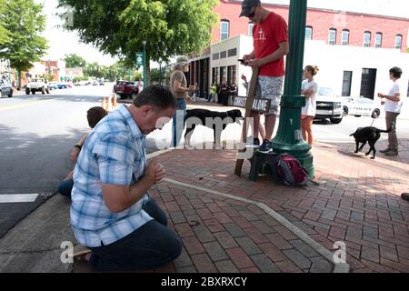 Jasper, Georgia, Stati Uniti. 7 Giugno 2020. I dimostranti Black Lives Matter si riuniscono fuori dal tribunale della contea di Pickens, nella zona rurale della Georgia settentrionale, per protestare contro la brutalità della polizia contro le minoranze. Sono stati accolti da contromanifestanti conservatori e sostenitori del presidente Trump che hanno guardato la manifestazione dall’altra parte della via principale di townÃs. Nella foto: Un uomo locale si inginocchia per pregare attraverso il rally BLM Credit: Robin Rayne/ZUMA Wire/Alamy Live News Foto Stock