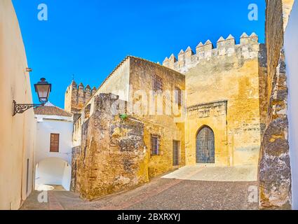 La stretta strada curva conduce alla porta medievale del castello Ducale con alti bastioni e merli conservati, Arcos, Spagna Foto Stock