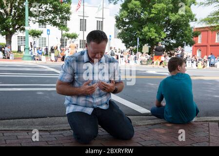 Jasper, Georgia, Stati Uniti. 7 Giugno 2020. I dimostranti Black Lives Matter si riuniscono fuori dal tribunale della contea di Pickens, nella zona rurale della Georgia settentrionale, per protestare contro la brutalità della polizia contro le minoranze. Sono stati accolti da contromanifestanti conservatori e sostenitori del presidente Trump che hanno guardato la manifestazione dall’altra parte della via principale di townÃs. Nella foto: Un uomo locale si inginocchia per pregare attraverso il rally BLM Credit: Robin Rayne/ZUMA Wire/Alamy Live News Foto Stock