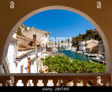 Cala Figuera vista porto incorniciato da villa terrazza patio arco con barche da pesca case e ville, Maiorca Isole Baleari Spagna Foto Stock