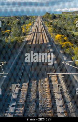 Binari ferroviari situati tra le montagne, visti dal ponte attraverso il cancello. Concetto di profondità e percorso. Foto Stock