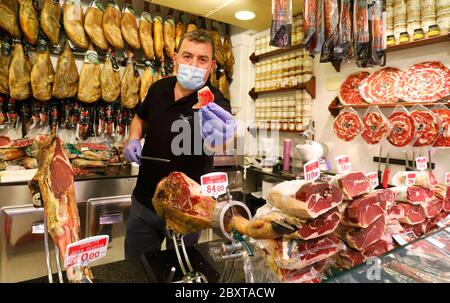 Palma, Spagna. 8 giugno 2020. Xisco mostra un pezzo di prosciutto in un negozio sul mercato Mercat de l'Olvivar. Dal 08.06.2020, nella 'fase 3' del relax delle misure corona, i negozi potranno ammettere più pubblico, sarà possibile consumare nei ristoranti e presso i banconi bar, tra l'altro. Credit: Clara Margais/dpa/Alamy Live News Foto Stock