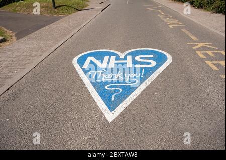 Grazie NHS in blu dipinto fuori Cobham scuola chiusa a causa di pandemia e divaricamento sociale a causa di coronavirus, strada vuota
