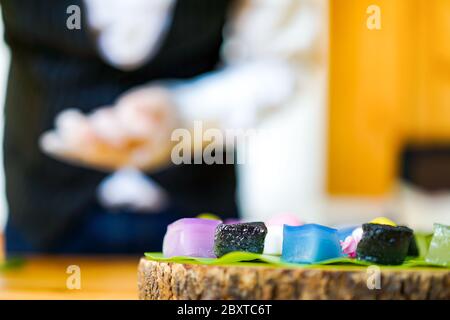 La mano dello chef tailandese sta decorando le varietà tradizionali e colorati dessert thailandesi, farina fumante, crema di crema nera, crema di cocco e fagioli fumanti, strato Foto Stock