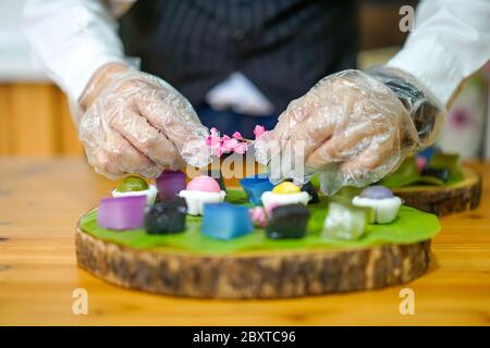 La mano dello chef tailandese sta decorando le varietà tradizionali e colorati dessert thailandesi, farina fumante, crema di crema nera, crema di cocco e fagioli fumanti, strato Foto Stock