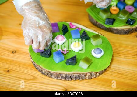 La mano dello chef tailandese sta decorando le varietà tradizionali e colorati dessert thailandesi, farina fumante, crema di crema nera, crema di cocco e fagioli fumanti, strato Foto Stock