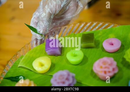 La mano dello chef tailandese sta decorando le varietà tradizionali e colorati dessert thailandesi, farina fumante, crema di crema nera, crema di cocco e fagioli fumanti, strato Foto Stock