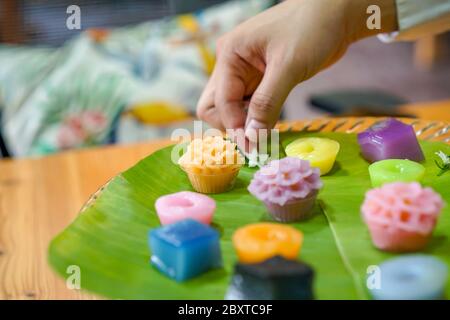 La mano dello chef tailandese sta decorando le varietà tradizionali e colorati dessert thailandesi, farina fumante, crema di crema nera, crema di cocco e fagioli fumanti, strato Foto Stock