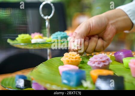 La mano dello chef tailandese sta decorando le varietà tradizionali e colorati dessert thailandesi, farina fumante, crema di crema nera, crema di cocco e fagioli fumanti, strato Foto Stock