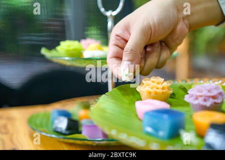 La mano dello chef tailandese sta decorando le varietà tradizionali e colorati dessert thailandesi, farina fumante, crema di crema nera, crema di cocco e fagioli fumanti, strato Foto Stock