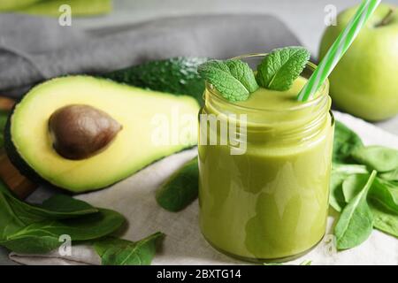 Spinaci all'avocado e frullato di mela verde bevanda tropicale sana e rinfrescante vista frontale primo piano di un vaso di vetro con foglie di menta e avocado a fette Foto Stock