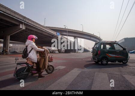 Pechino 北京 / Cina 国 : Donna in casco rosa guida moto sotto la quarta strada anulare Foto Stock