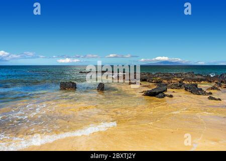 Vista oceano con grandi rocce nere da Kamaole Beach sull'Isola Hawaiiana di Maui Foto Stock