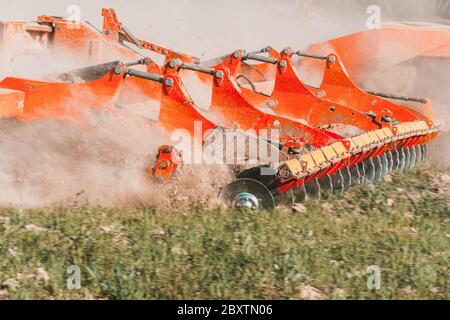 L'attrezzatura agricola riduce la terra arata. Un trattore cingolato tira un erpice per allentare il terreno da vicino. Foto Stock