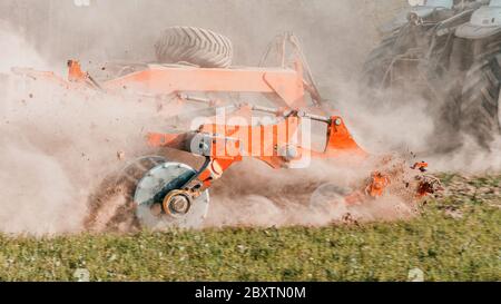 L'attrezzatura agricola riduce la terra arata. Un trattore cingolato tira un erpice per allentare il terreno da vicino. Foto Stock