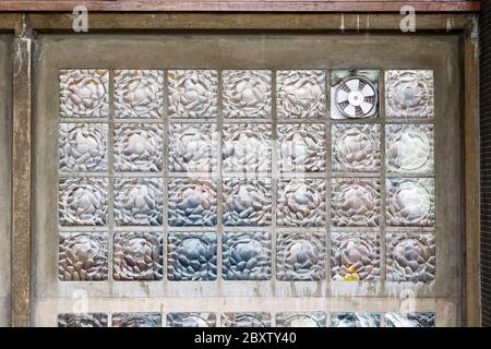 Ventola di aspirazione per ventilazione installata su una parete di blocco in vetro per l'uso in background Foto Stock