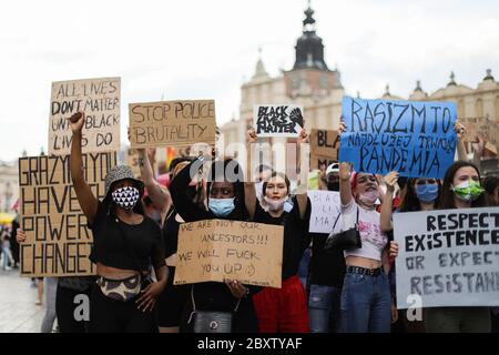 Giovani manifestanti con maschere di sfuso tengono cartelli con slogan che condannano il razzismo.centinaia di giovani hanno partecipato alla protesta 'Black Lives Matter' a Cracovia, la più grande città della Polonia meridionale. Hanno reso omaggio a George Floyd ed hanno espresso la loro disapprovazione per la brutalità e il razzismo della polizia. Foto Stock