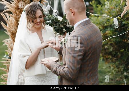 Sposo mettendo l'anello di nozze sul dito della sposa. Sposa e sposo. Cerimonia nuziale. Foto Stock