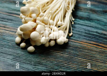 Enoki, Enokitake, vellutipi flammulina, funghi commestibili popolari in cucina giapponese. Mucchio di funghi bianchi serviti su sfondo di legno blu, Foto Stock