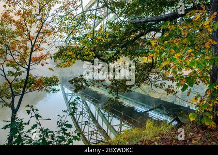 Route 9 Bridge e riflesso attraverso gli alberi e la nebbia di mattina presto nel fiume Connecticut con coloratissime foglie autunnali, a Brattlebro, New Hampshire Foto Stock