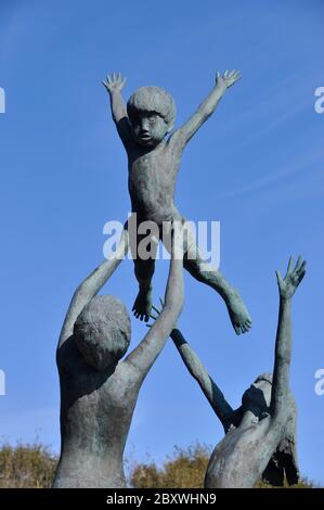 Una scultura in bronzo di David Wynne di tre bambini in gioco nei giardini dell'abbazia di Tresco sull'isola di Tresco. Isole di Scilly.Cornovaglia Foto Stock