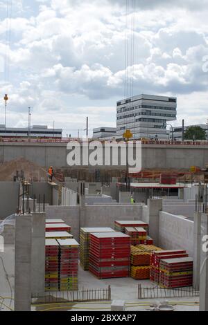 Cantiere con fondazione in cemento davanti a un moderno edificio bianco sotto il cielo nuvoloso Foto Stock