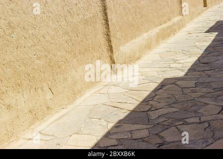 Antico sfondo stradale con pareti in materiale adobe e pietre da pavimentazione. Vicino Oriente o asia centrale vecchio paese rurale Foto Stock