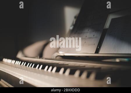 Basso scatto di 88 tasti di una tastiera e spartiti. Primo piano con la luce laterale Foto Stock