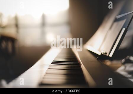 Lunghezza di 88 tasti di tastiera a pianoforte all'interno di una casa con luce dorata del mattino Foto Stock