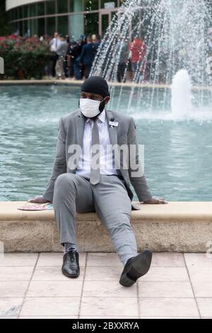 Un giovane uomo che indossa una maschera faccia prende una pausa prima di entrare nella chiesa della Fontana di lode durante una visita pubblica per George Floyd. La morte di Floyd, due settimane fa, per mano di un ufficiale di polizia bianco a Minneapolis, ha generato centinaia di proteste contro il razzismo e la brutalità contro la polizia in tutto il mondo. Foto Stock