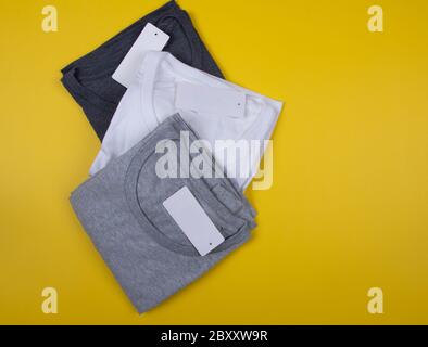 T-shirt grigio scuro, grigio e bianco su sfondo giallo brillante. Foto Stock